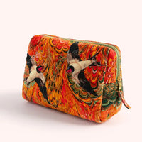 Close-up of a colorful velvet cosmetic bag with swallow design and orange mosaic pattern