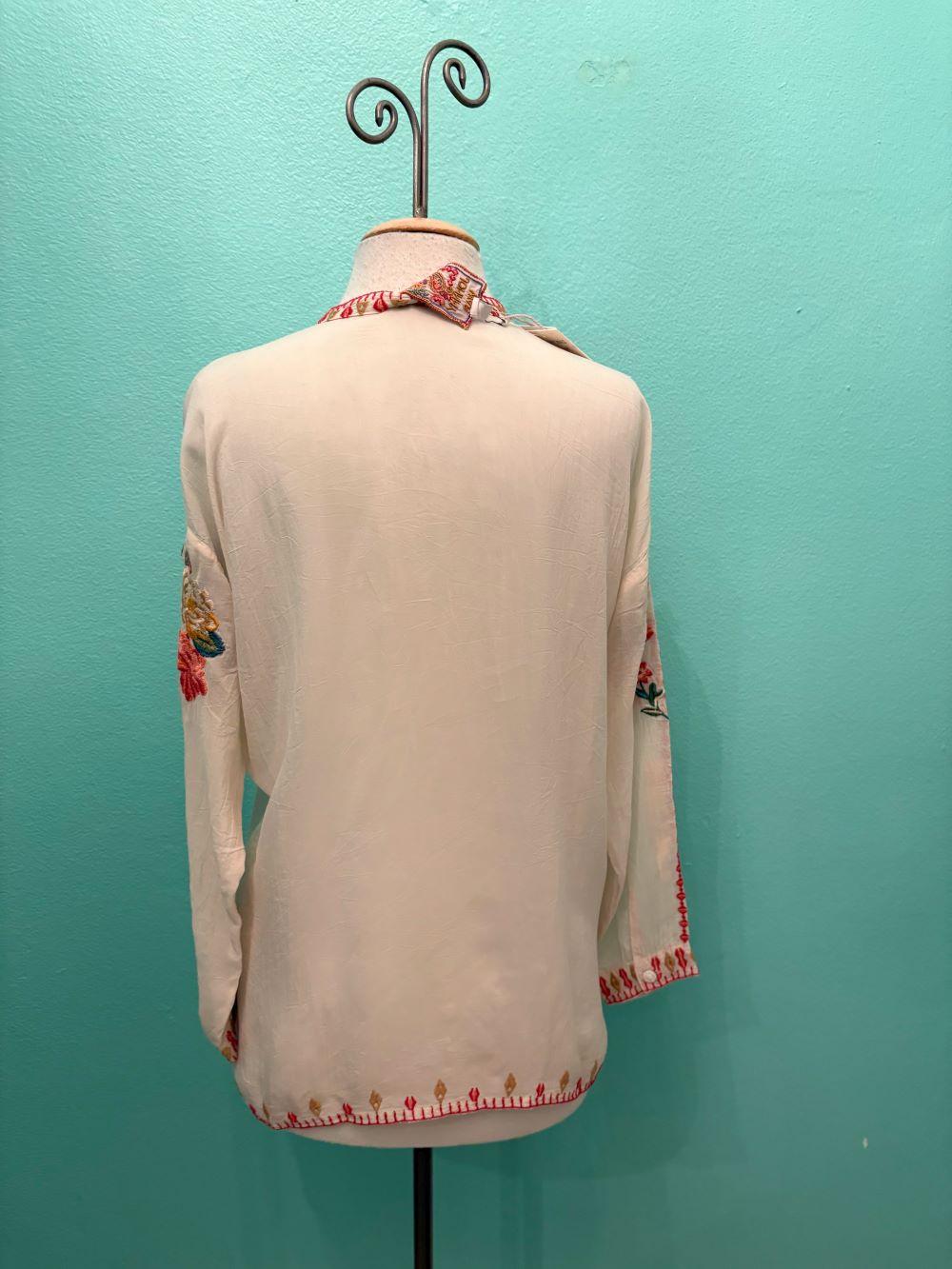 Back view of a cream blouse with colorful embroidered details
