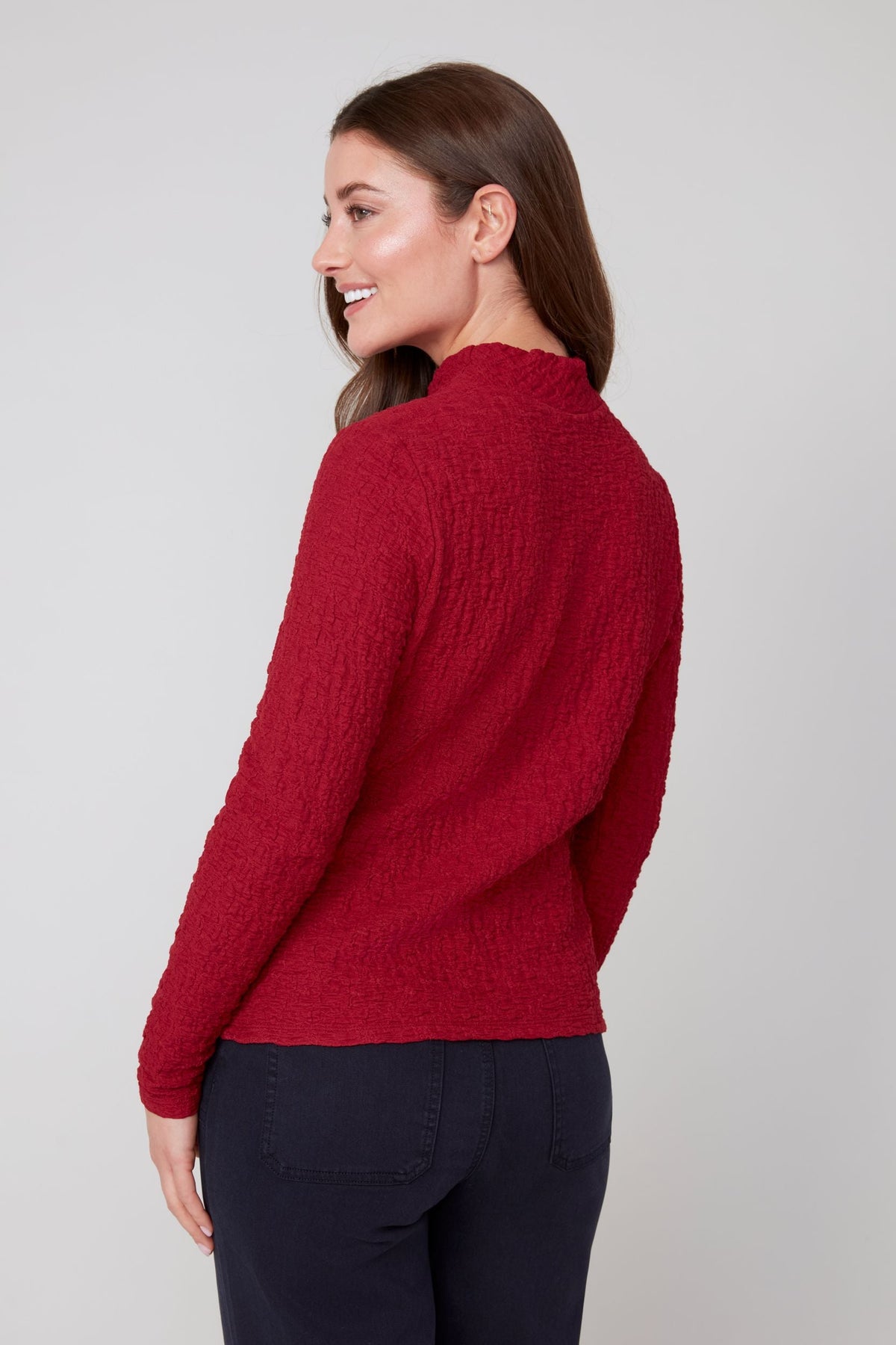 Back view of woman wearing a crimson textured long sleeve mock neck top