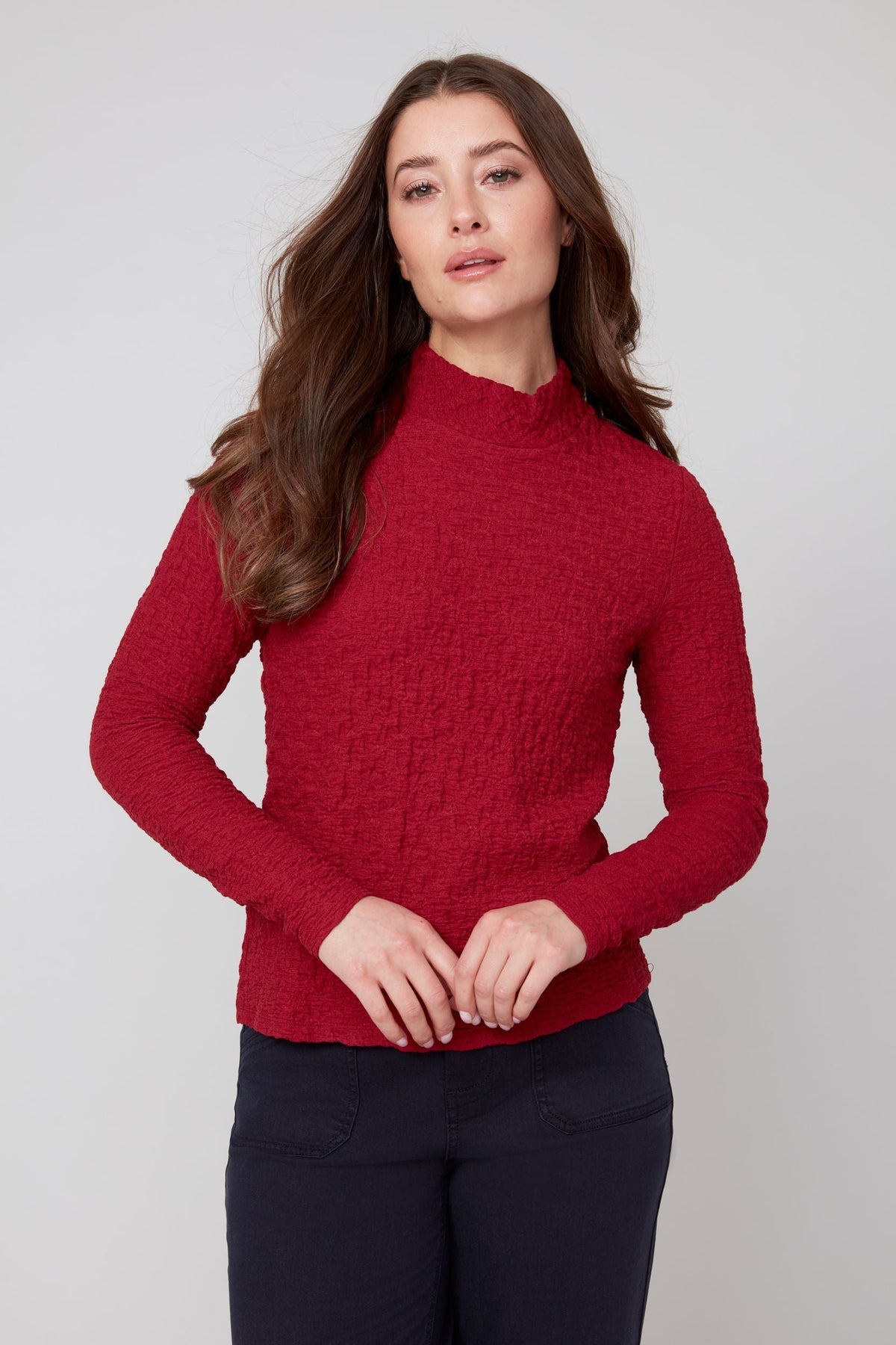 Front view of woman wearing a crimson textured long sleeve mock neck top