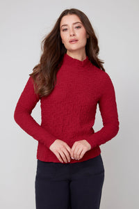 Front view of woman wearing a crimson textured long sleeve mock neck top