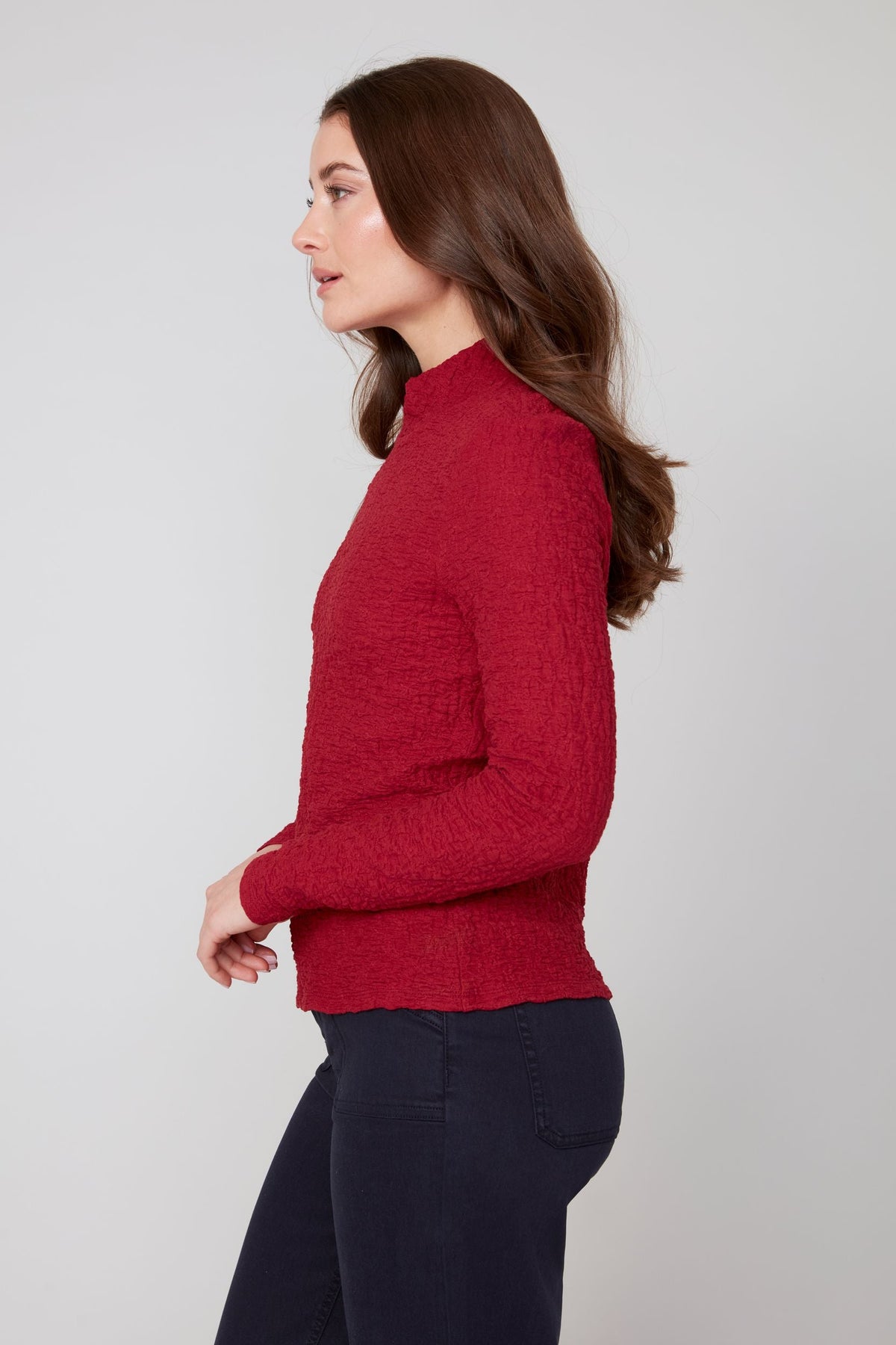 Side profile of woman in a crimson textured mock neck top with long sleeves