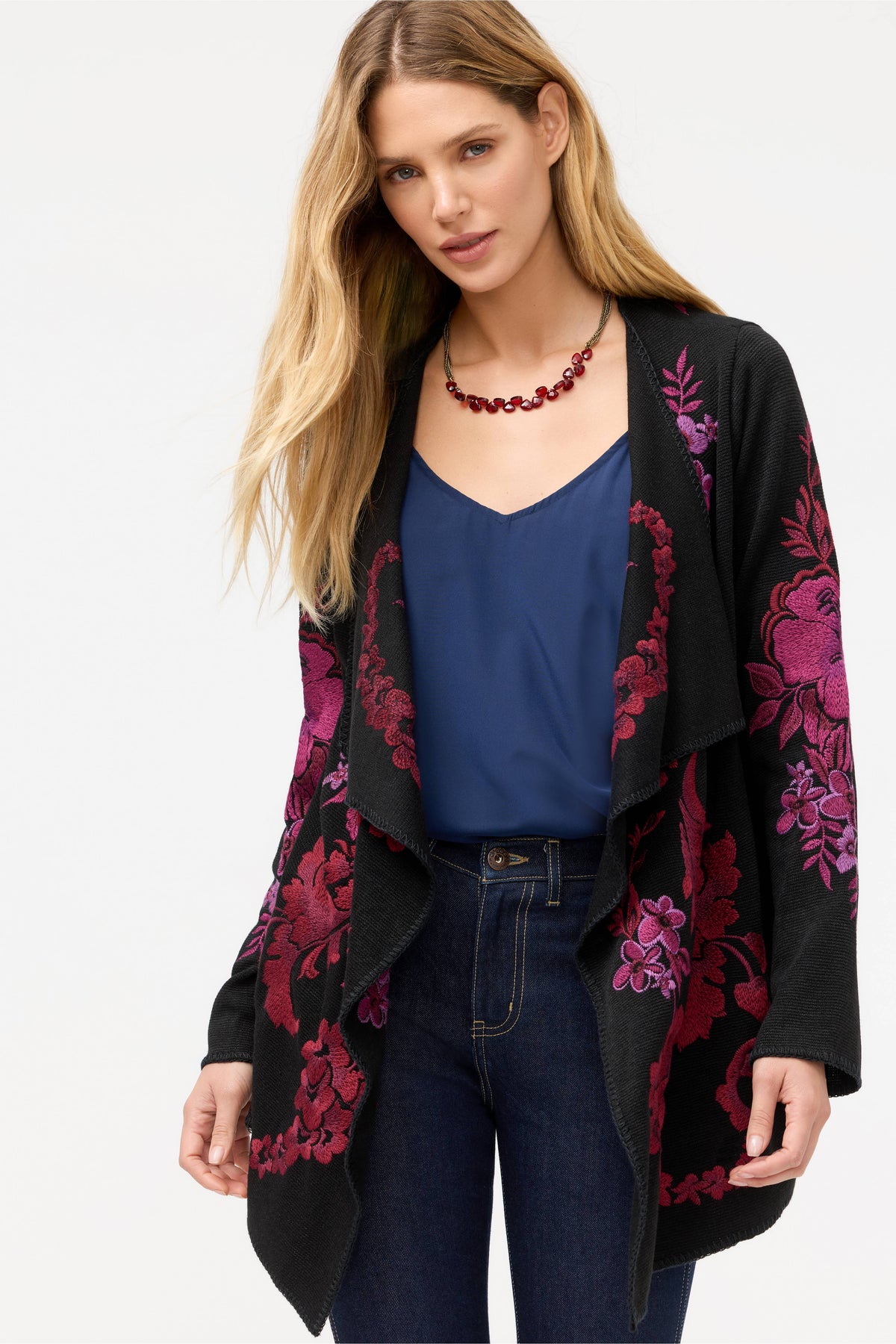 Front close-up of embroidered cardigan with bold floral designs in magenta and purple over black fabric