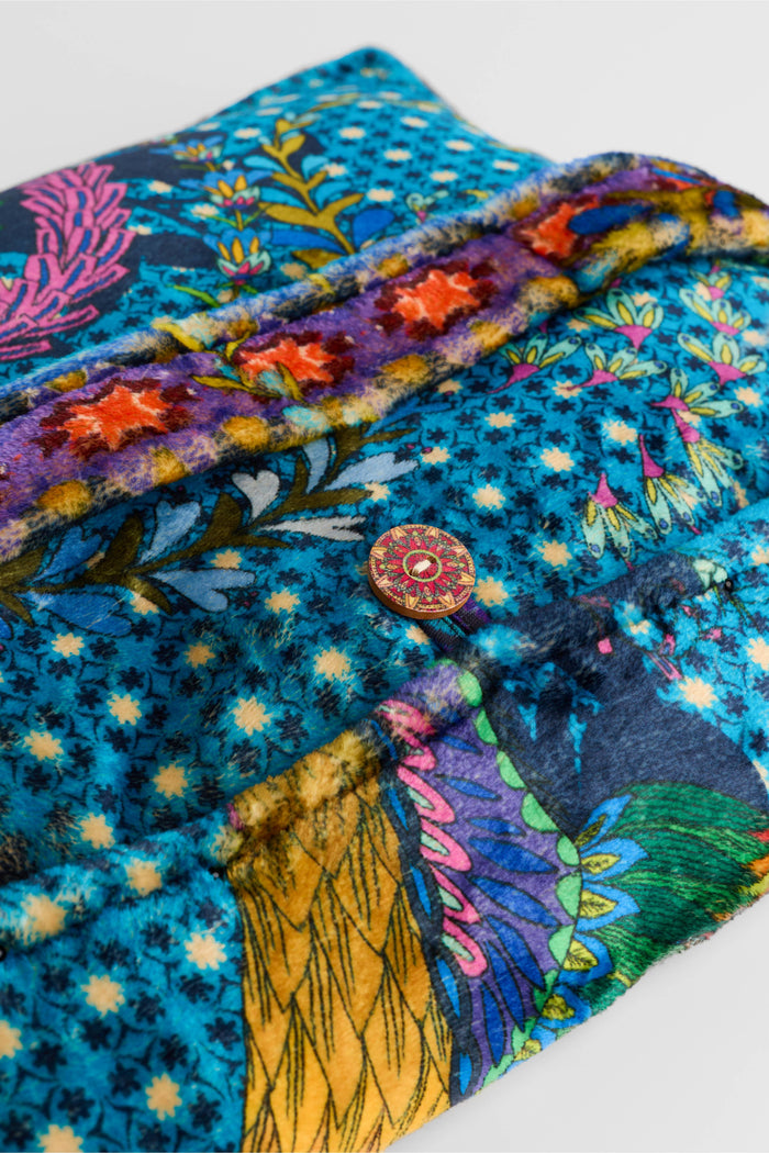 Closeup of vibrant travel pouch in blue with floral button and star-patterned trim