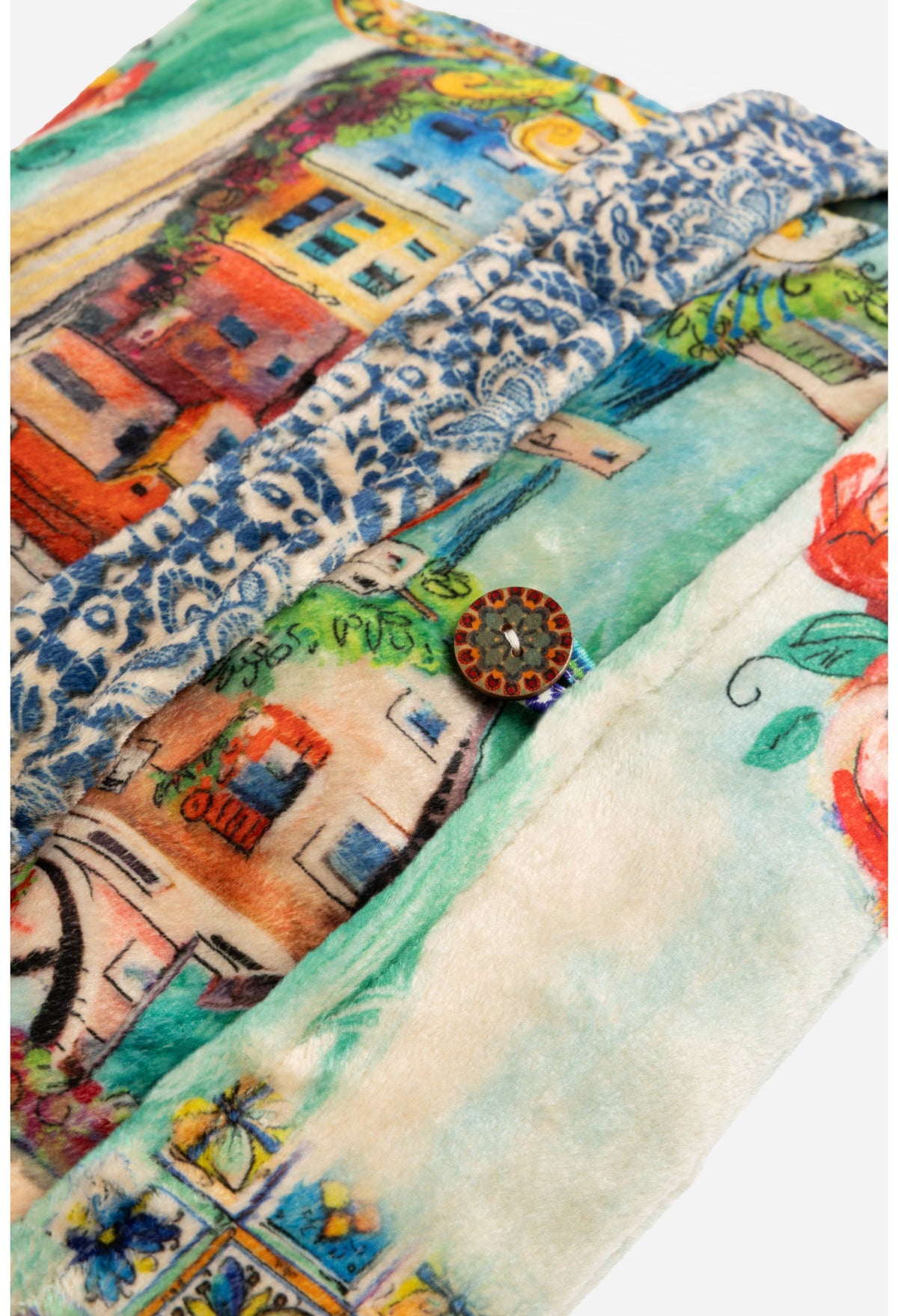 Close-up of colorful button and village details on travel blanket