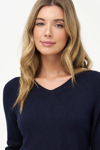 Close-up of a woman in a navy V-neck sweater, showing detail and neckline