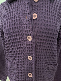Close-up of textured navy cardigan with buttons and front pockets