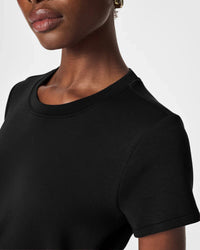 Close-up of the soft round neckline and short sleeves of a black dress