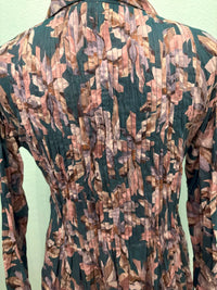 Close-up view of pleated forest leaf print fabric on the back of a long sleeve dress