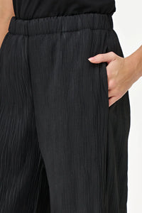 Close-up of hand in pocket showing black wave-textured pants and elastic waistband