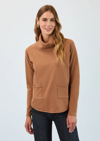 Close-up of a woman in a camel funnel neck pullover highlighting the soft fabric and dual pockets