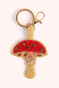 Close-up of an embellished mushroom-shaped keychain with red beads and gold sequins