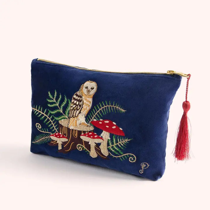Close-up of blue velvet pouch featuring embroidered owl, ferns, and red mushrooms