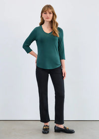 Woman wearing emerald green 3/4 sleeve V-neck top with black pants