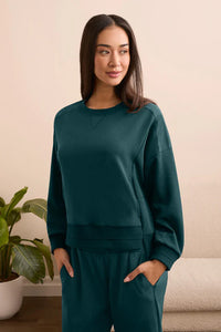 Woman wearing emerald green lounge set, relaxed fit and soft fabric, standing indoors
