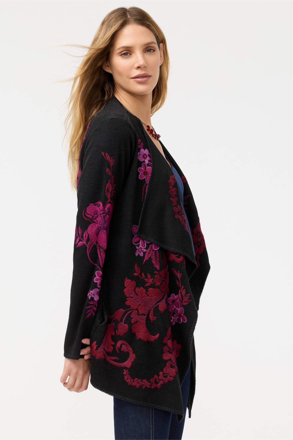Side view of model in floral embroidered black cardigan, highlighting detailed magenta and purple flowers