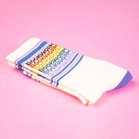 Folded white socks with purple accents and rainbow 'BOOKWORM' text on a pink background