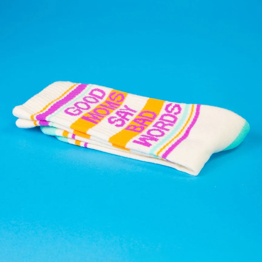 Folded cream socks with 'Good Moms Say Bad Words' on a blue background