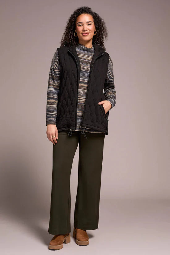 Front view of woman modeling a black quilted hooded vest with her hand in one pocket