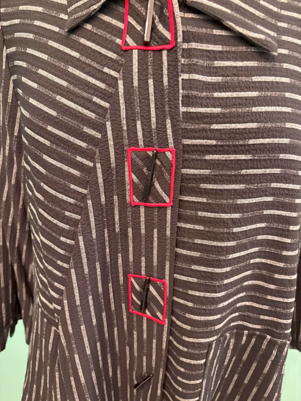Detailed close-up of front buttons and red-stitched buttonholes on a striped jacket