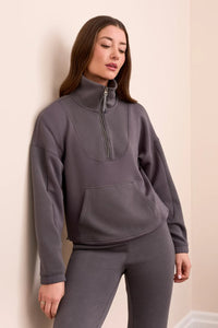 Close-up front view of woman in a slate grey quarter-zip ribbed lounge top and pants