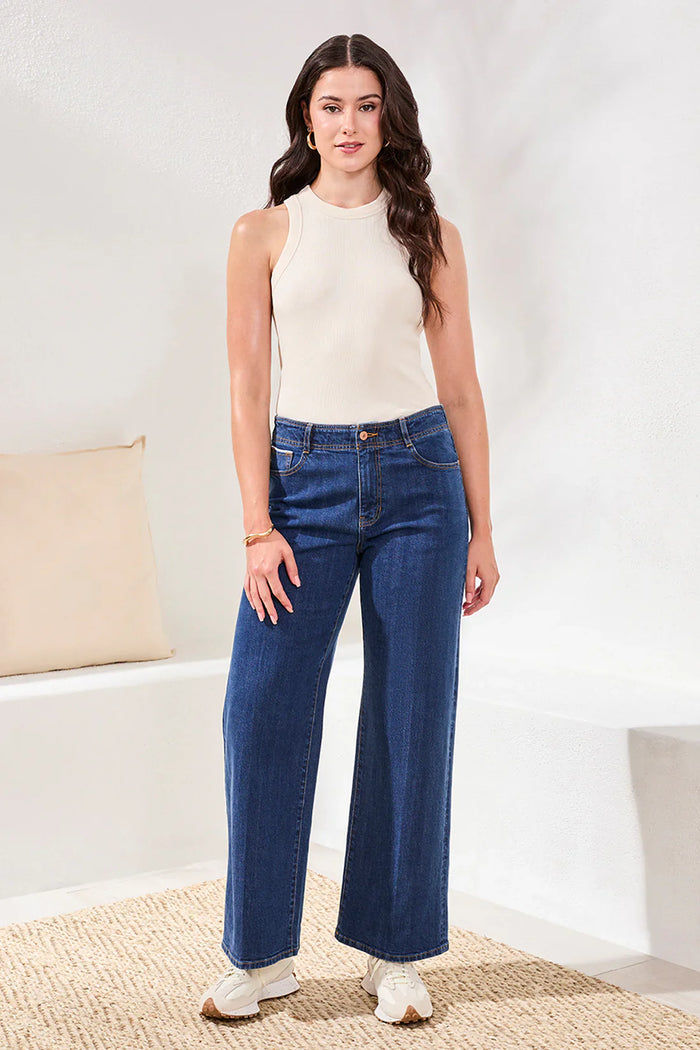 Full front view of woman modeling wide-leg blue denim jeans and cream top