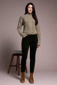 Front view of woman modeling olive corduroy pants with chunky sweater