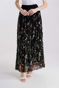 Front view of black floral embroidered maxi skirt, styled with white sandals