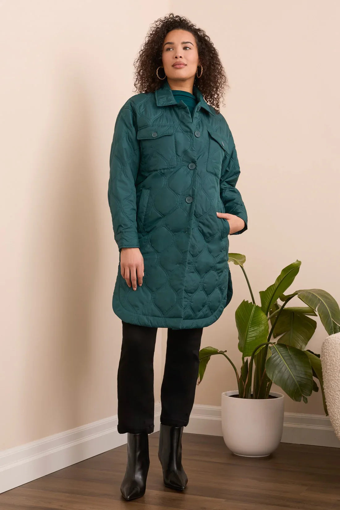 Front view of a woman showcasing an evergreen quilted longline jacket with pockets and button details.
