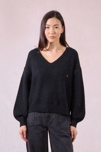 Front view of woman wearing black V-neck sweater with subtle sparkling details
