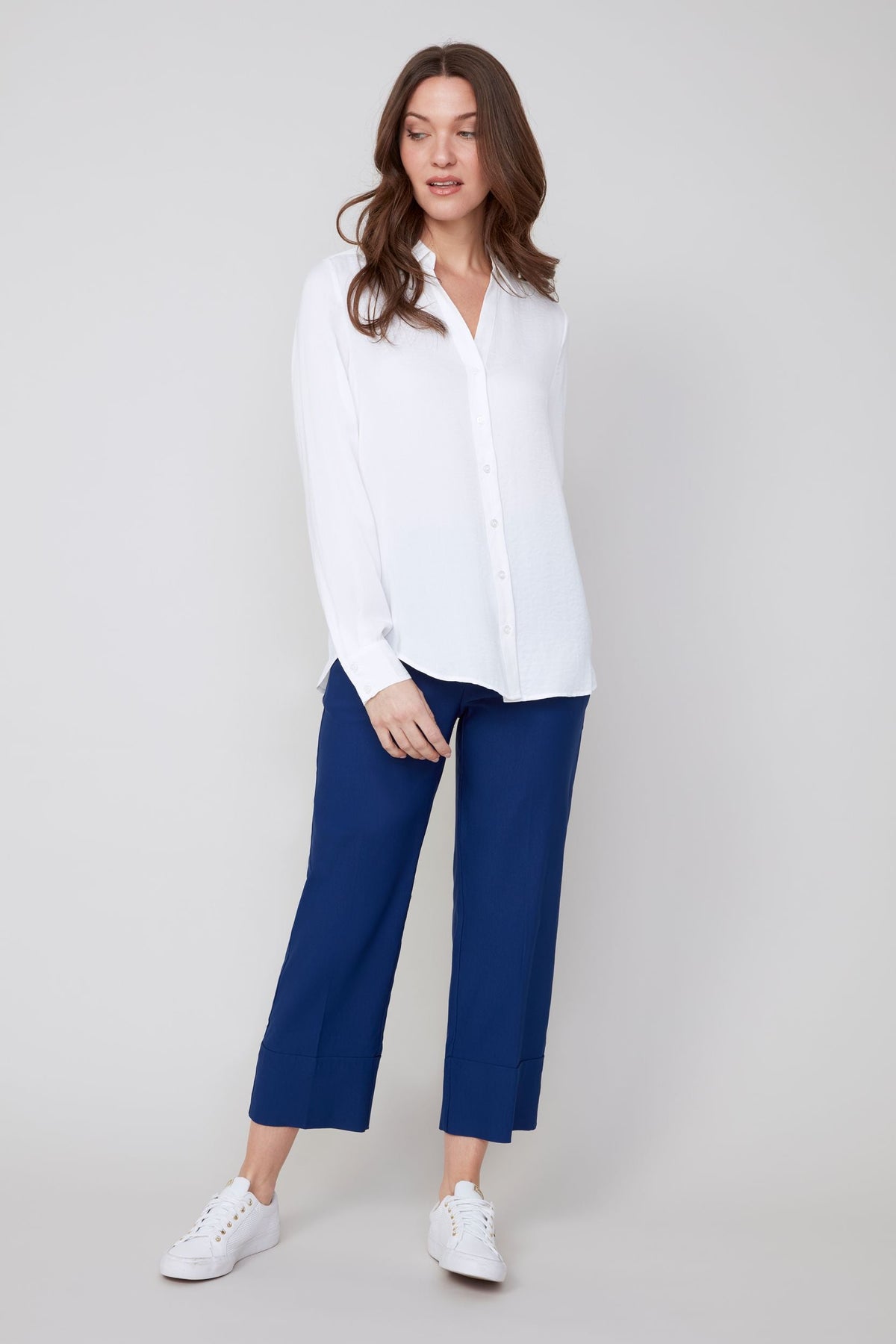 Front view of woman in white button-up blouse and blue cropped pants