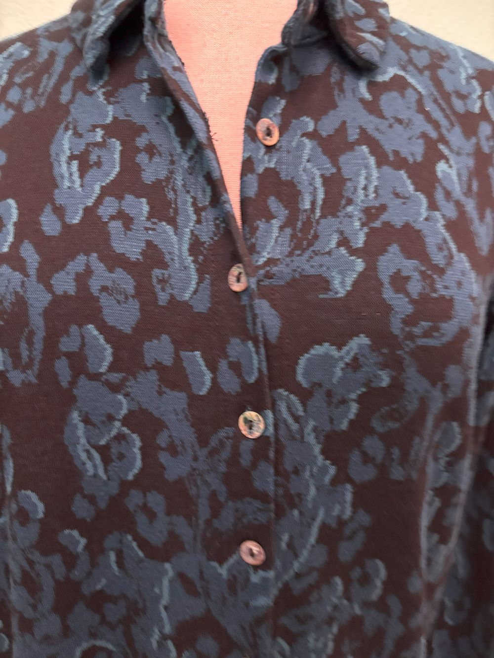 Front view of navy blue floral button-up shirt with collar displayed on mannequin