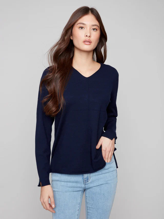 Front view of woman in navy v-neck sweater paired with light blue jeans