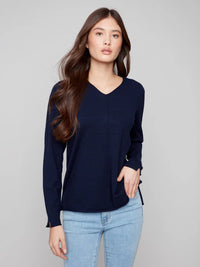 Front view of woman in navy v-neck sweater paired with light blue jeans