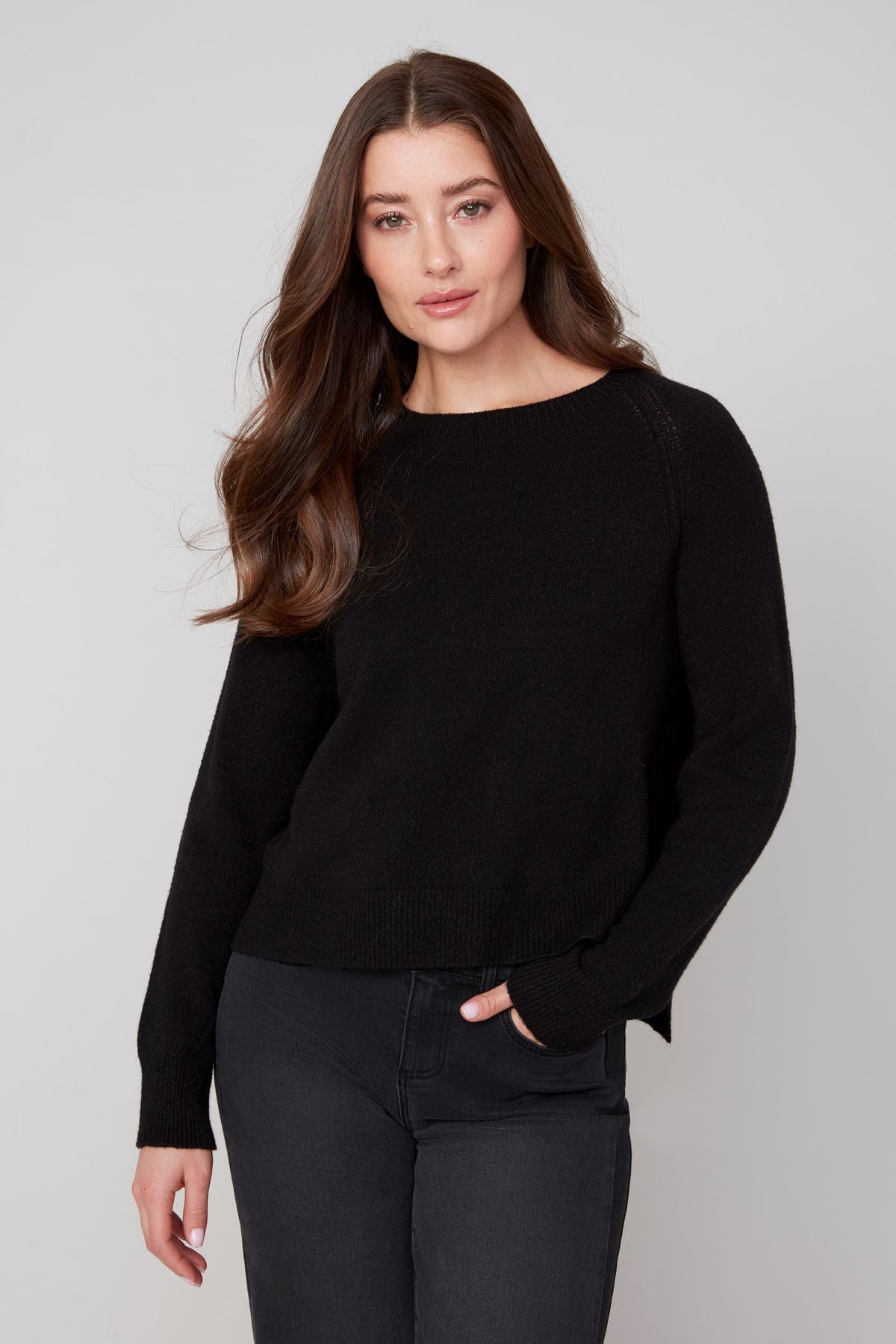 Front view of a woman modeling a sleek black crewneck sweater