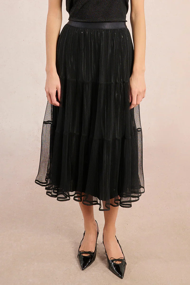 Front view of black mesh pleated midi skirt styled with black top and patent heels