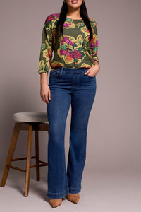 Front view of woman standing in classic flare stretch blue jeans and floral blouse