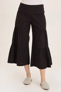 Front view of flowy black wide-leg culotte pants with tiered design