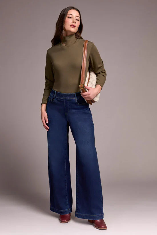 Model in wide leg jeans with olive turtleneck and shoulder bag, front pose