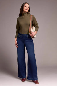 Model in wide leg jeans with olive turtleneck and shoulder bag, front pose