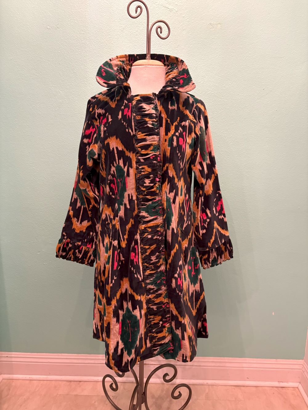 Front view of the velvet coat with ruched detailing and bold Ikat pattern on mannequin