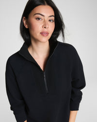 Woman wearing a black quarter-zip pullover, front view with zipper detail