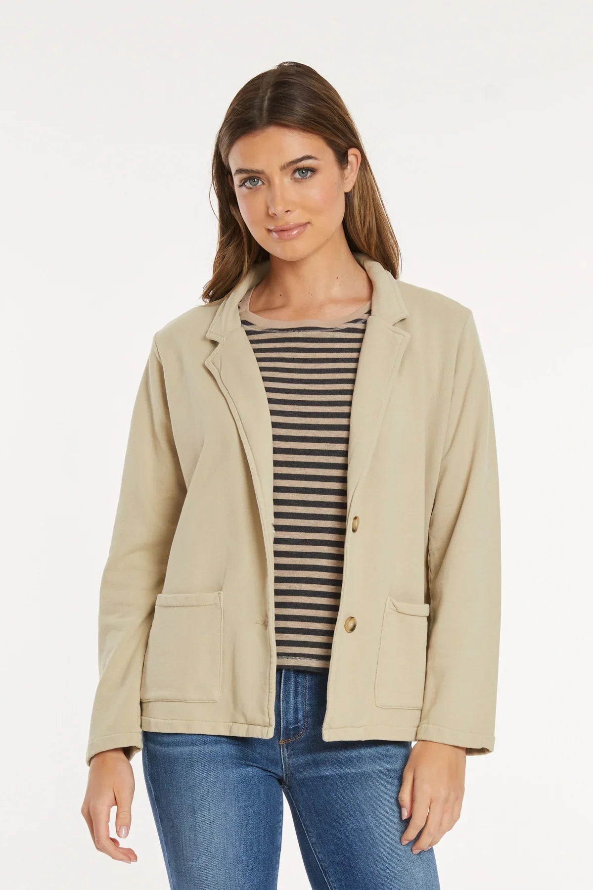 Woman wearing beige knit blazer over striped top, front view