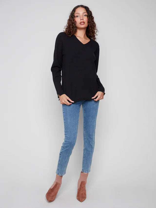 Standing woman in a black V-neck sweater and light blue jeans
