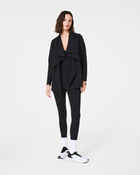 Full body view of woman modeling black drape front cardigan with leggings and sneakers