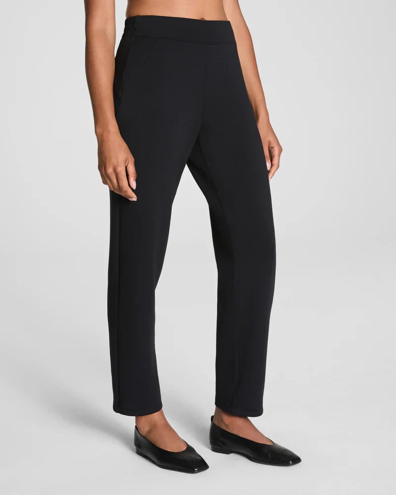 Full length view of black stretch tapered pants paired with flats