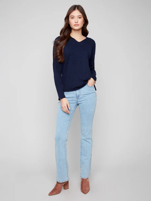 Full body shot of woman in navy v-neck sweater and light blue jeans with brown boots