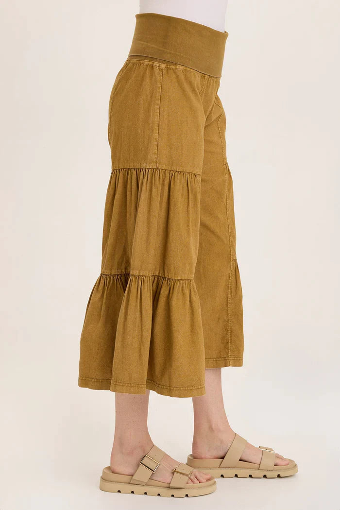 Side view of golden tiered pants showcasing flared and ruched legs