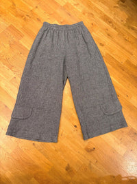 Heather grey wide leg linen pants with flap pockets laid flat on wooden floor
