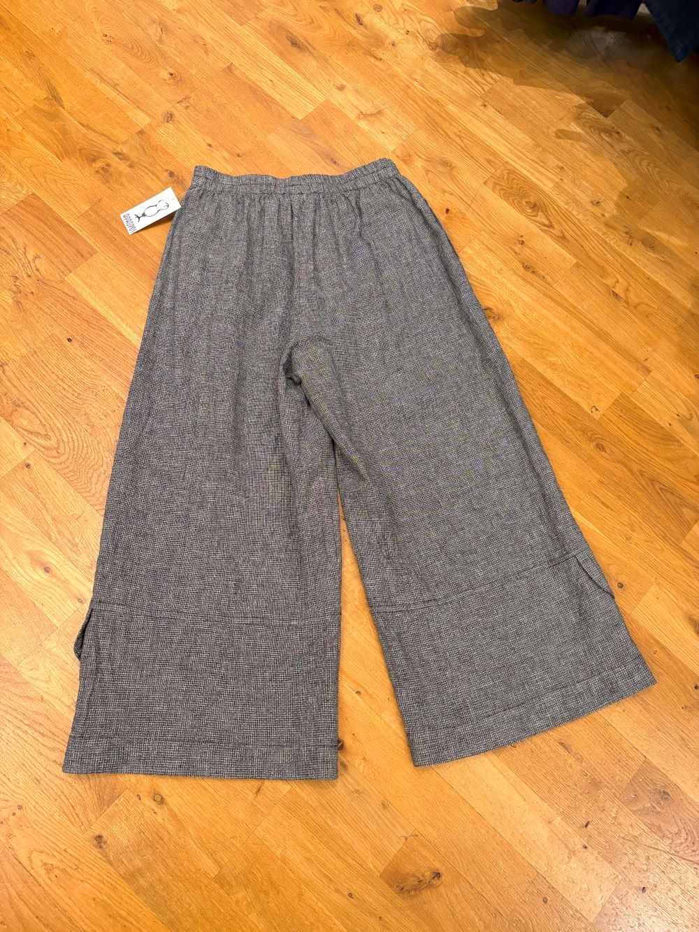Heather grey wide leg linen pants with elastic waistband displayed on wood floor